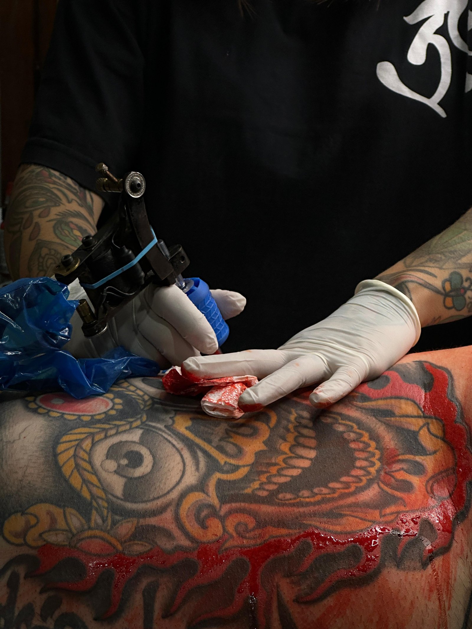 Marilia tatuando, close da mão com a máquina em cima da pele